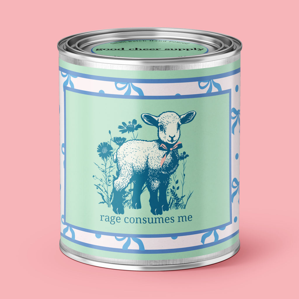 An Unhinged Paintball Candle with a peaceful lamb with the phrase "Rage Consumes Me" on a green and white background with blue ribbons. 