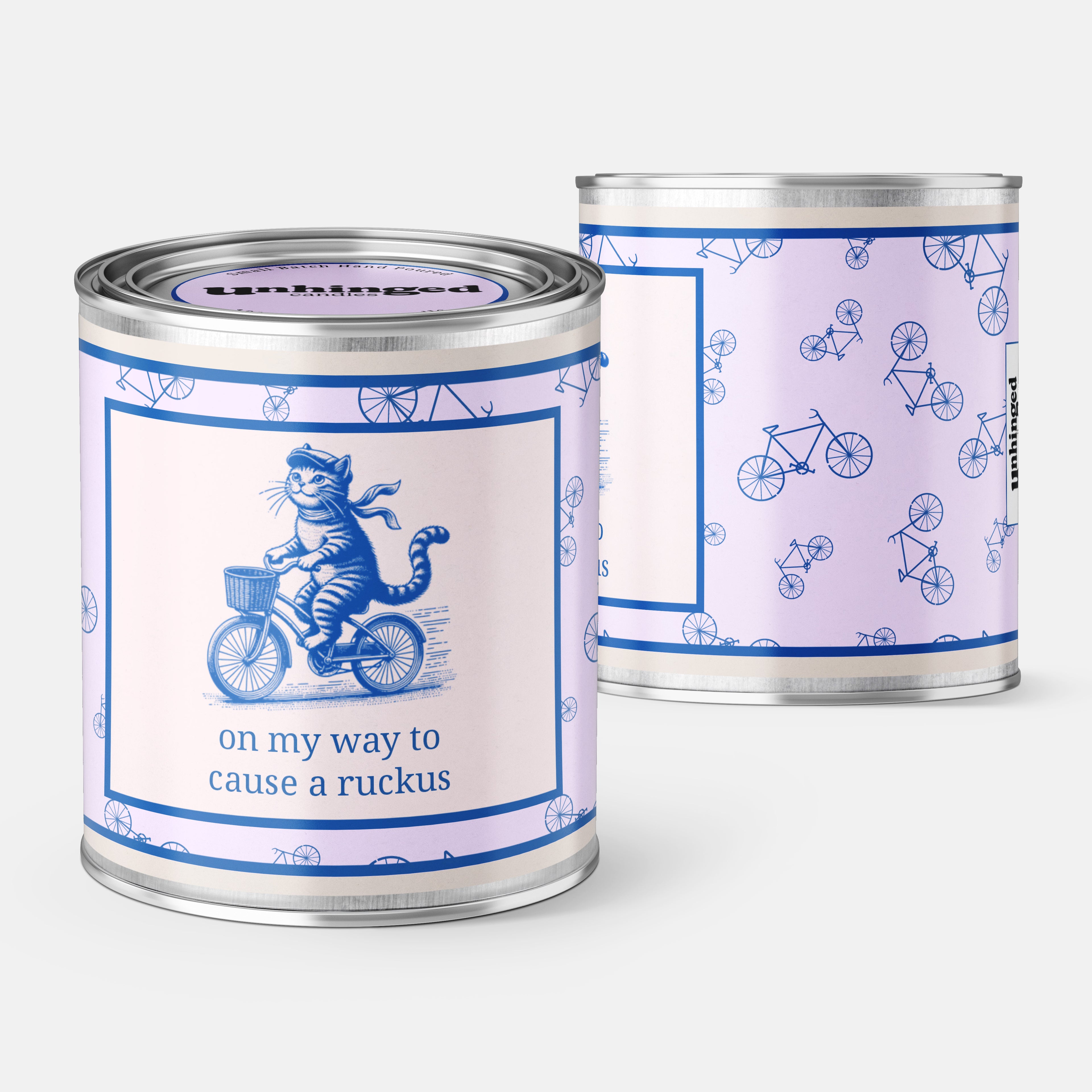 front and back pic An Unhinged Paintcan candle with a picture of a happy cat riding a bike with the phrase "on my way to cause a ruckus" printed on it. 