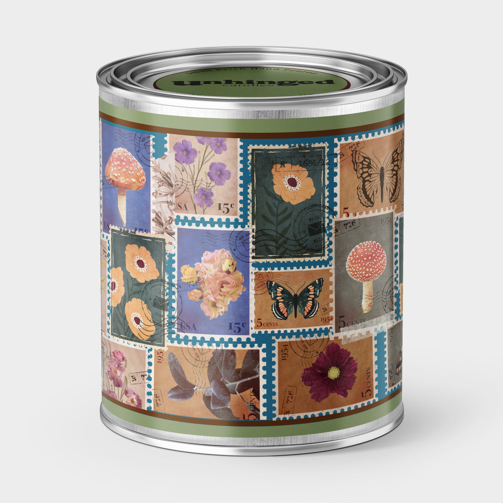 An Unhinged candle Paint can candle  with decorative design featuring postage stamps of flowers, mushrooms  and butterflies.
