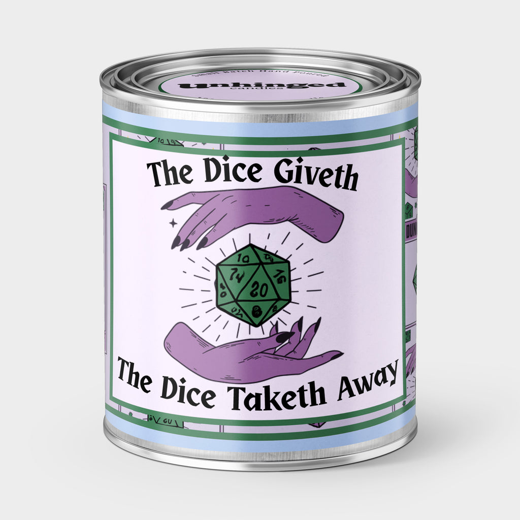 An Unhinged Paintcan candle with phrase 'The Dice Giveth, The Dice Taketh Away' label featuring two hands surrounding a D20 die on a lavender background. D&D Dungons & Dragons RPG 